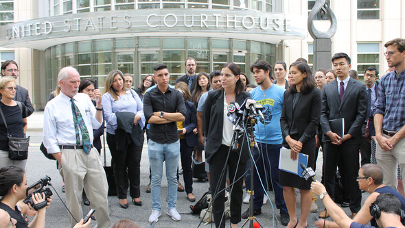 A group of clinic students and clients stand in front of a courthouse at a press conference