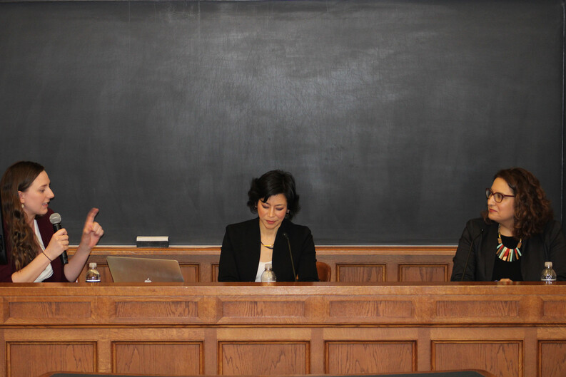 Moderator Maggie Lemons ’25 speaks into a microphone, seated next to speakers Karen Tani and Jasmine Harris