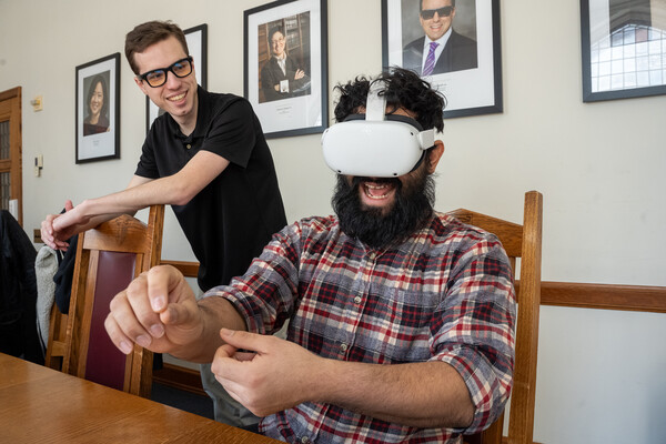 one person tries a virtual reality headset while another watches