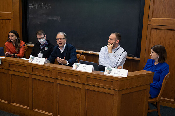 A group of five panelists seated at the front of a classroom talking