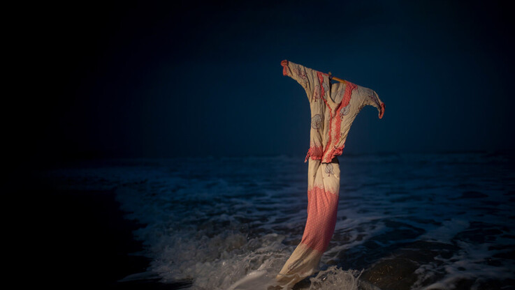 pink and cream colored dress against ocean waves at night