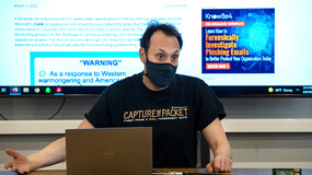 Professor Scott Shapiro in his cybersecurity class, seated in front of a screen with a projected news story on ransomware.