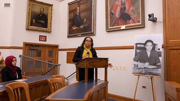 Speaker at podium next to portrait of Jane Bolin